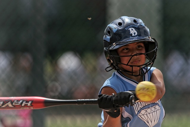 A young softball player about to hit an incoming pitch.